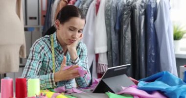 Frustrated female seamstress sits at a table in a tailor shop, close-up. Defect in the work of the tailor, error in the design of clothes