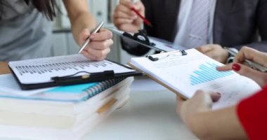 Colleagues in the office are discussing charts in folders, close-up. Business associates, financial analysis of the project