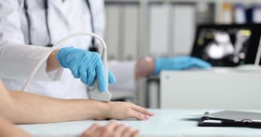Kadın bir doktor kolun ultrasonunu çeker, yakından, yavaş çekimde. Eldeki damarların hastalıklarının teşhisi