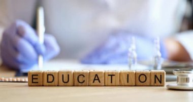 On the table in the clinic, wooden cubes with the inscription education, close-up. Medical training of students