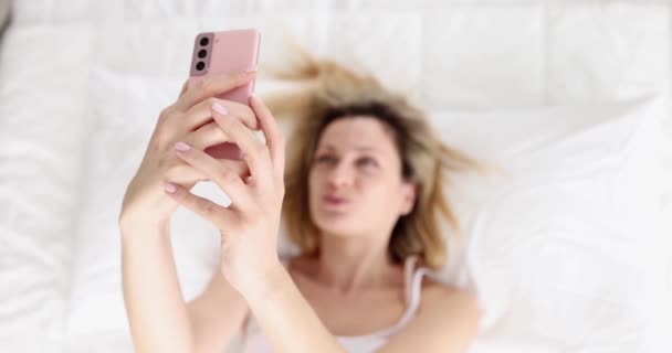Woman Lying Her Back Bed Takes Selfie Smartphone Video Communication — Stockvideo