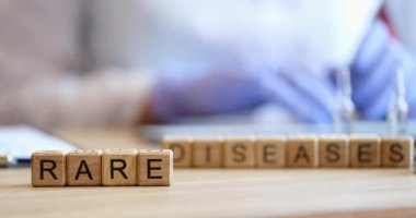 Doktorun üzerinde ender rastlanan hastalıklar yazan tahta küpleri var. Yakın plan. Hastanın haklarını korumak, genetik hata