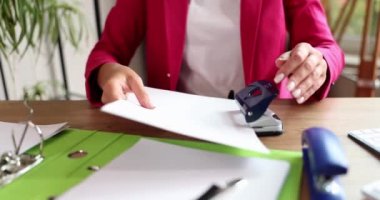 Businesswoman fastening important papers with hole punch closeup 4k movie slow motion. Paper work concept