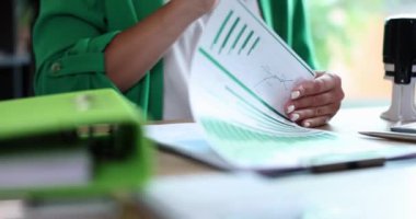 Businesswoman studying documents with graphs and putting seal on them closeup 4k movie slow motion. Official certification of important documents concept