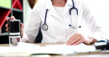 Doctor putting stamp on document in clinic closeup 4k movie slow motion. Certification of official documents in medicine concept