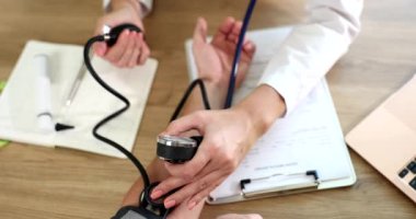 Doctor therapist measuring blood pressure to patient in clinic using tonometer closeup 4k movie slow motion. Diagnosis and treatment of arterial hypertension concept