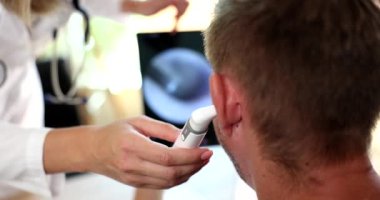Doctor otorhinolaryngologist examining patient ear using modern digital otoscope closeup 4k movie slow motion. Diagnosis and treatment of otitis media concept
