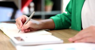 Woman accountant counting on calculator and writing down data in notebook closeup 4k movie slow motion. Accounting and audit concept