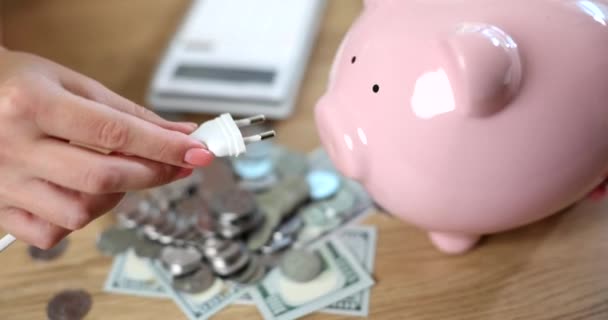 Hand Inserting Electric Plug Piggy Bank Money Closeup Movie Slow — Stockvideo