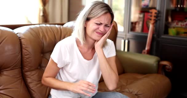 Woman Sitting Sofa Holding Hand Cheek Area Diseased Tooth Movie — Αρχείο Βίντεο