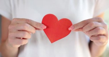 Female hands holding red paper heart closeup 4k movie slow motion. Volunteer help concept