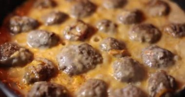 Pork meatballs in creamy tomato sauce cooked in pan closeup 4k movie slow motion. Rustic cuisine recipes concept