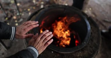Homeless man warming his hands by fire on street closeup 4k movie slow motion. Life of people without fixed place of residence concept