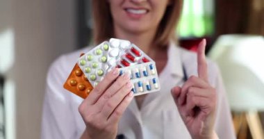 Doctor showing index finger and holding lot of medicine blisters closeup 4k movie slow motion. Recommendations for regular medication intake concept