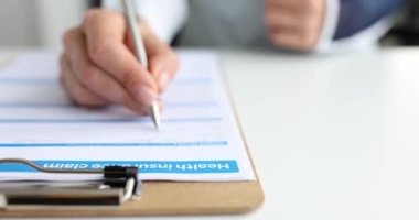 Eli yaralanmış bir müşteri sağlık sigortası talep formunu doldurur. Tedavi maliyetleri kavramının geri ödenmesi
