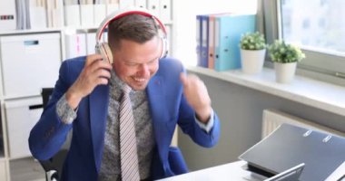 Takım elbiseli genç adam kulaklık takıyor ve ofis filminde dans ediyor. Başarılı iş konsepti