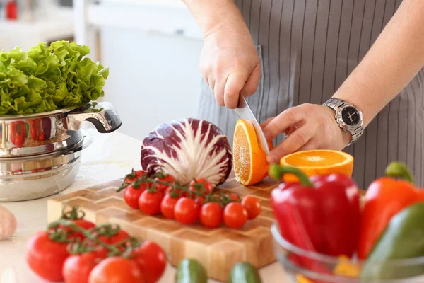 Mutfakta kesme tahtasıyla portakal kesen şeflerin yakın çekimi. Sağlıklı yemek ve vitamin salatası.