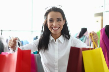 Alışveriş merkezindeki alışveriş torbalarıyla gülümseyen genç kadın. Mutluluk tüketim indirimleri ve satışlar mağazada