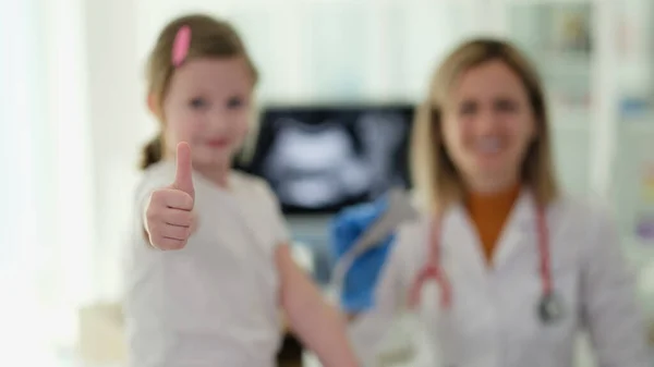 小さな女の子は医師の診察で親指でジェスチャーをする 質の高い小児科医のサービス — ストック写真
