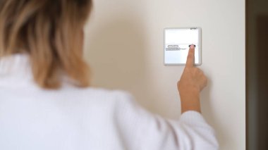 Duvara monte edilmiş dijital klima kontrolü ve ev termostatı. Kadın parmakları oturma odasında konforlu sıcaklık ayarlama derecelerini yakınlaştırır