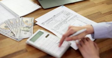Kadın, ABD 1040 vergi formunu el yazısıyla ve hesap makinesi kullanıyor. Bireysel vergi iadesi vergisi ve konsept ödeme zamanı