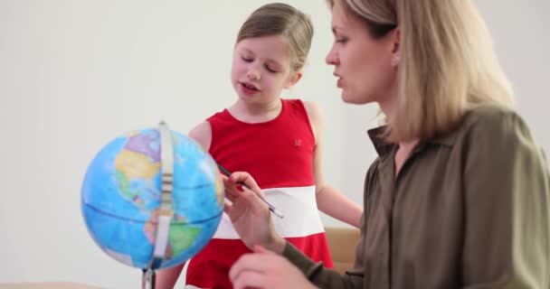 好奇心旺盛な少女とポジティブな女性は テーブルで地球を見ています 学生は 明るい前提で母親と世界地図を探索しています 地理的スローモーションのレッスン — ストック動画