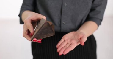 Kadın ışık stüdyosunda duran deri çantadan gümüş paralar döküyor. Küçük tasarruf ve bütçe kavramı. Yoksulluk ve düşük ücretler yavaş çekim