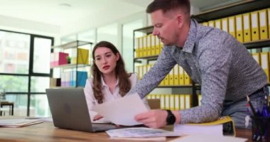 İş yerindeki ahşap masadaki modern dizüstü bilgisayar monitörüyle ilgili bilgileri çok sıkı çalışan meslektaşlar gözden geçirir. Çalışanlar yeni projede yavaş çekimde çalışıyorlar