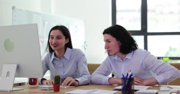 积极的员工乐于完成复杂的项目 年轻男女们一边笑一边挥手 坐在办公桌前 办公室里拿着电脑 — 图库视频影像
