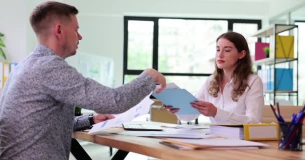 男性と女性の従業員は オフィスの木製のテーブルに座っているチャートを含む文書を使用しています 企業のスローモーションにおける論文との連携 — ストック動画