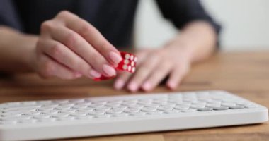 Çıplak kadın eli, kırmızı zarları beyaz klavyeye, tahta masaya koyar. Taşınabilir tuş takımında kırmızı şeffaf fildişi olan aynı noktalar