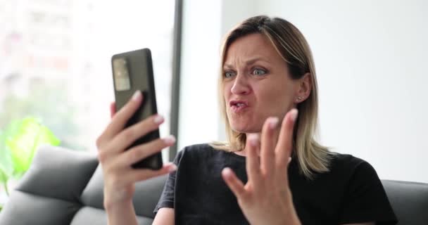 女人在手机屏幕上看在线通信时 在家里说脏话 女人怒气冲冲地看着智能手机慢动作 — 图库视频影像