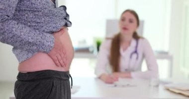 Doktor-doktor, erkek hasta üst bedenini belirlenen randevuda kontrol ediyor. Adam, hastanede ağır çekimde aylık kontrol sırasında karın ağrısı gösteriyor.