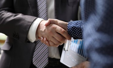 Close-up of businessman and businesswoman handshaking. Partners signing important and profitable agreement, contract. Business meeting and negotiations concept clipart