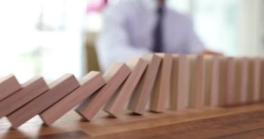 Düşen sıradan figürler, ahşap masanın üzerindeki kırmızı tahta blok tarafından durduruldu. Müşteri sigortası ve kişisel kaza sigorta hizmetleri kavramı. Domino etkisi