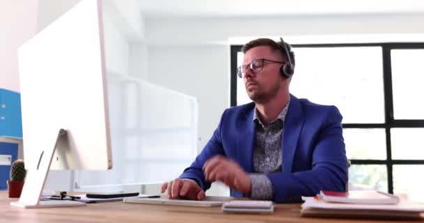 コンピュータ経由で同僚とのオンラインミーティングでヘッドフォンを着用するエグゼクティブマネージャー ビジネスマンのCeoは オフィスのスローモーションでコンピュータに取り組んでいます — ストック動画