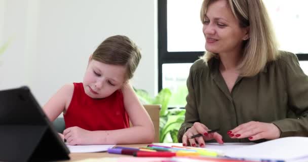 年轻女人帮助小女儿做作业 女学生笑着写女学生坐在桌旁 慢吞吞地笑着 图库视频片段