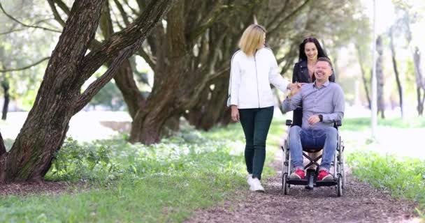 휠체어에 남자와 공원에서 사람들은 즐겁게 말하고 손으로 남성은 슬로우 모션을 — 비디오