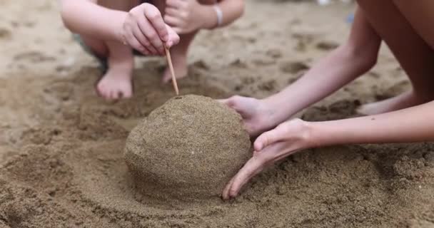 母亲和小女儿在海滩上用沙子构筑结构 女孩的插入粘在建筑物里 与家人一起玩乐 一起放松慢动作的概念 — 图库视频影像