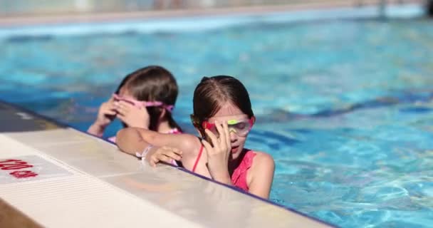 女孩子们在浅水深的游泳池里调整泳镜 旅馆区儿童娱乐娱乐的概念 — 图库视频影像