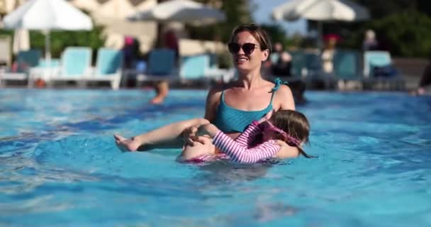母亲在旅馆的游泳池里抱着女儿 享受海滨慢动作休闲度假乐趣的概念 — 图库视频影像
