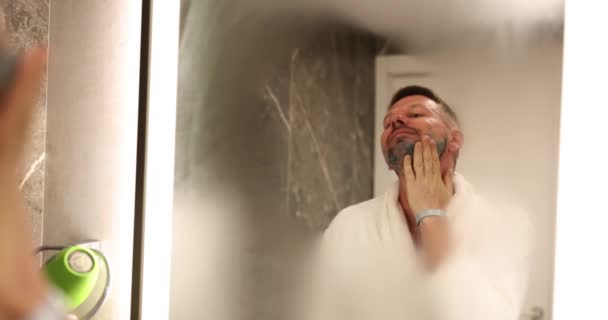 Focused Man Applies Shaving Gel Face Looking Fogged Mirror Apartment — Stock Video