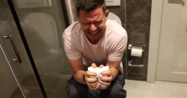男性は痛みのポップのために懸命にプッシュします 男はトイレットペーパーを手で締める 消化器の問題と毎日のトイレトリートメントの遅い動き — ストック動画