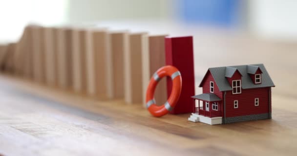 ブイと赤い木製のブロックがテーブルの上のおもちゃの家に落ちる 顧客保護および事故保険に関するコンセプト ホーム 保護保険 — ストック動画