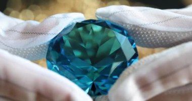Brilliant cut blue diamond in hands of jeweler in gloves. Blue diamond and shades