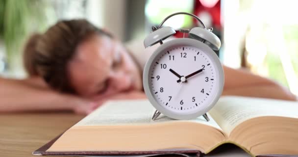 书架上的闹钟响了 女人睡在后面 学习和丧失动力的教育时间概念 — 图库视频影像