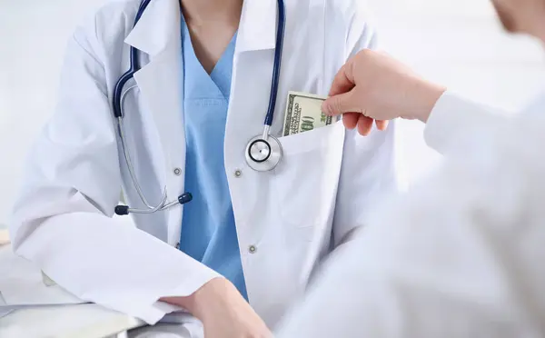 Female doctor hold in hands bunch of hundred dollars banknotes take or give them. Prestige and high paid job encash treatment illegal drug fraud anonymous visitor private visit reform concept