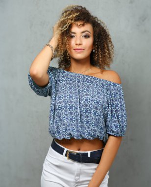 Güzel siyah kadın portre. Bir gri arka plan ve gülümseyen güzellik moda stil kıvırcık saçlı beyaz lifler görünüm göz kamera ile değer