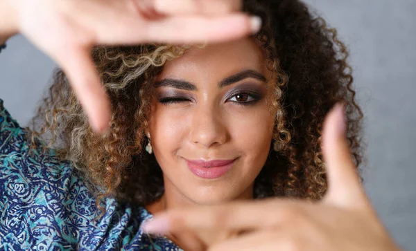 Beautiful black woman portrait. She put her hand around the frame as if she were photographing a beauty fashion style curly hair with white locks eyes look into the camera