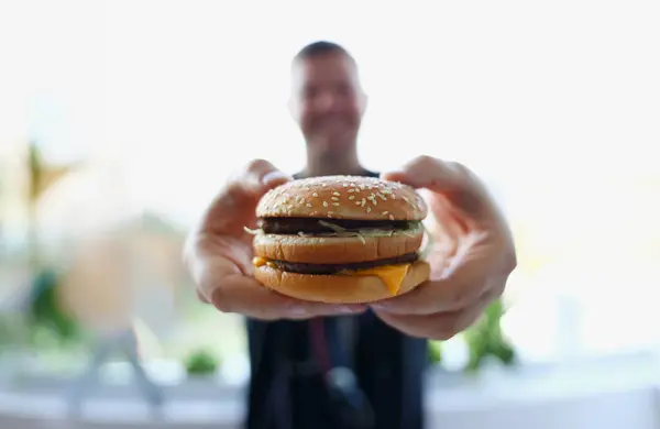 Tevreden Jonge Man Met Een Hamburger Zijn Handen Het Kantoor — Stockfoto